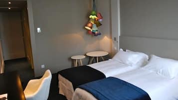 A hotel room with a bed, two bedside tables, a chair, and a colorful hanging light fixture.