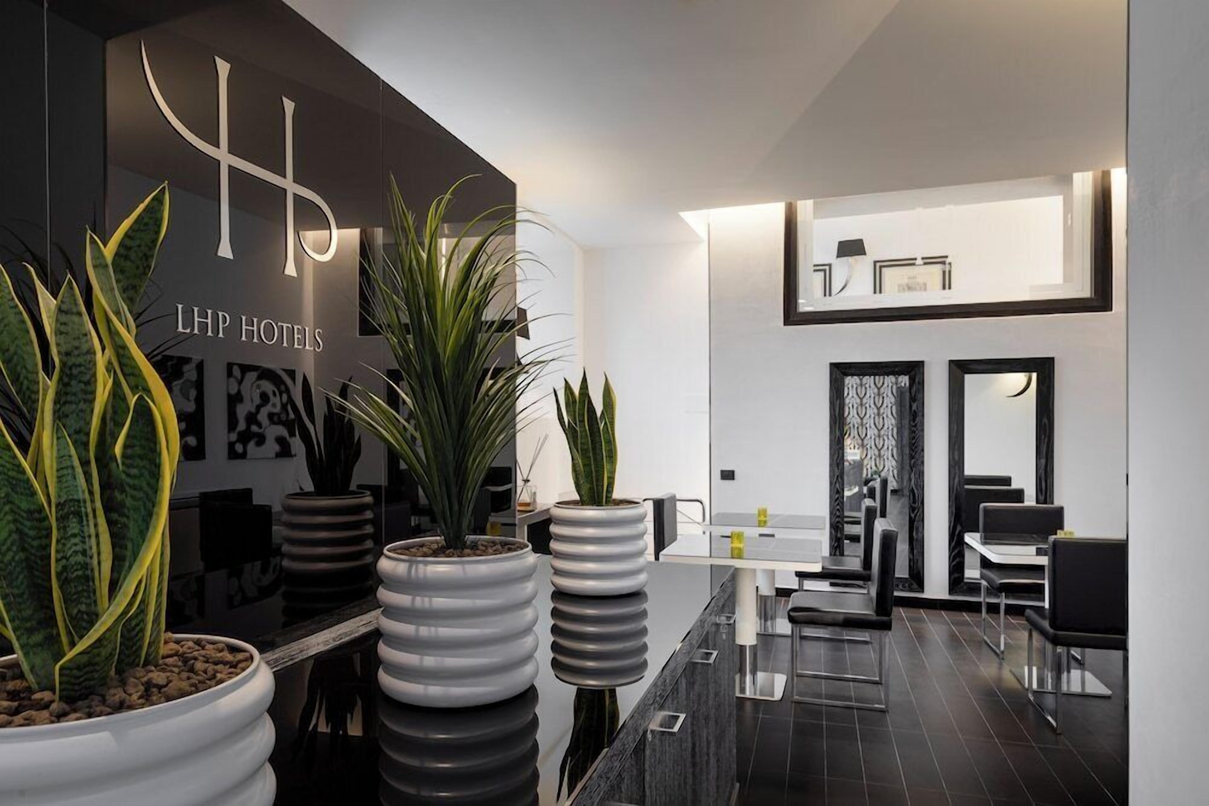 Una hall d'hotel moderna con una reception, piante in vaso e una zona relax.