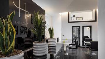 Una hall d'hotel moderna con una reception, piante in vaso e una zona relax.