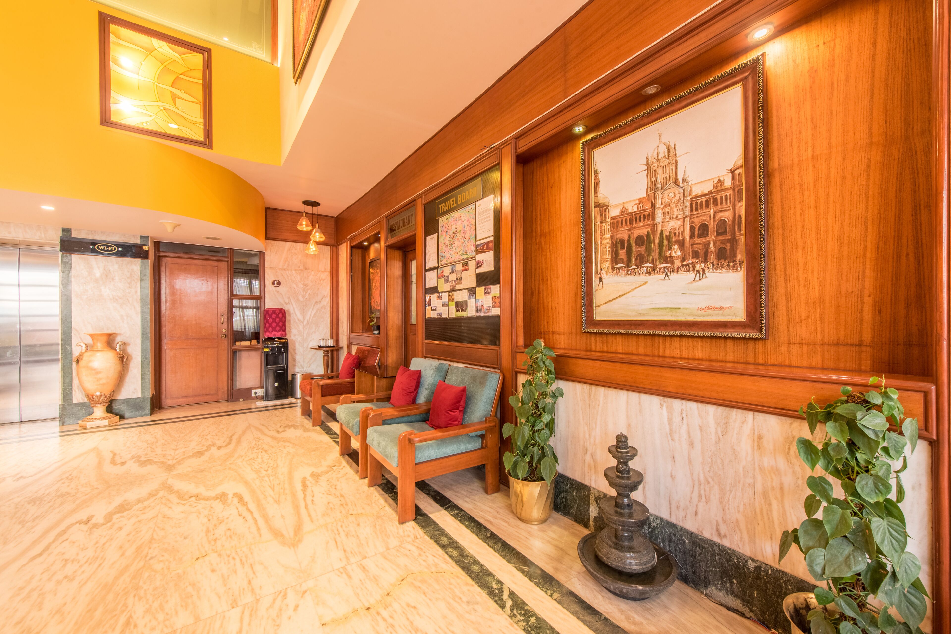A lobby with a marble floor, wooden furniture, a large framed picture, and a reception desk.