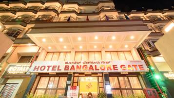Hotel Bangalore Gate features a traditional exterior with balconies and windows, surrounded by lush greenery.