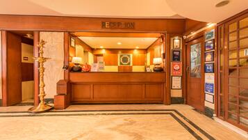 A reception area with a wooden reception desk, a wall-mounted clock, and a sign indicating the reception.