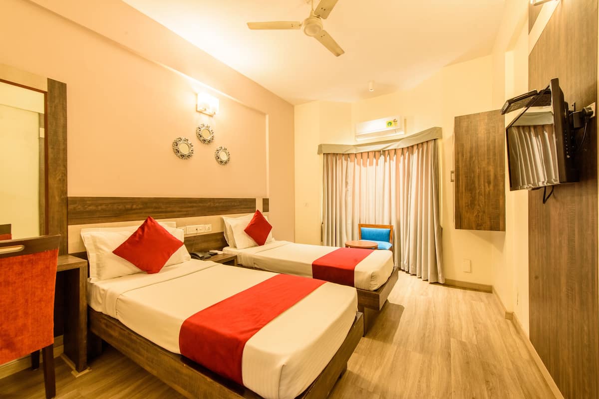 A hotel room with two beds, a ceiling fan, a TV, and a desk with a chair.