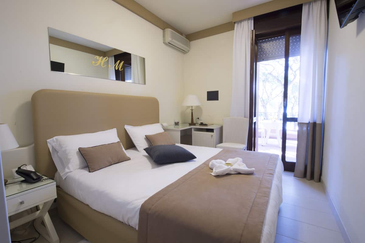 Une chambre d’hôtel avec un grand lit, une table de chevet avec une lampe, un bureau et une chaise.