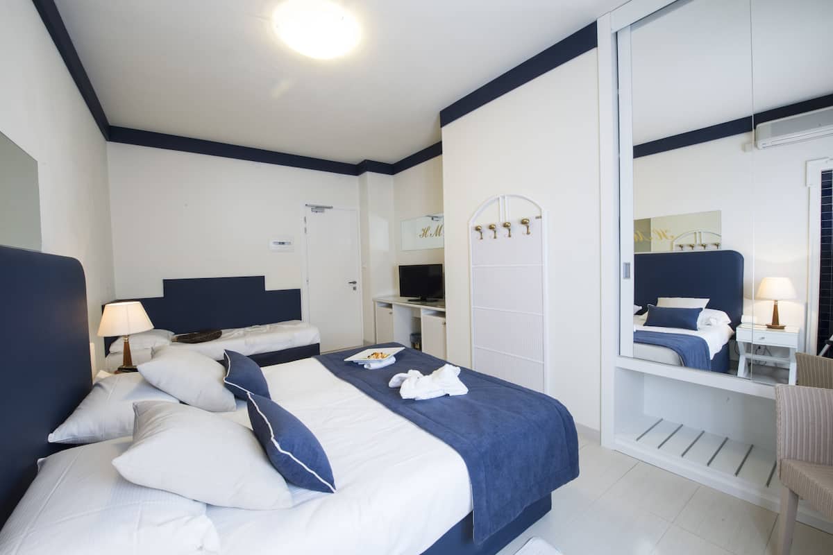 Une chambre d’hôtel avec un grand lit, un bureau, un miroir et une chaise.