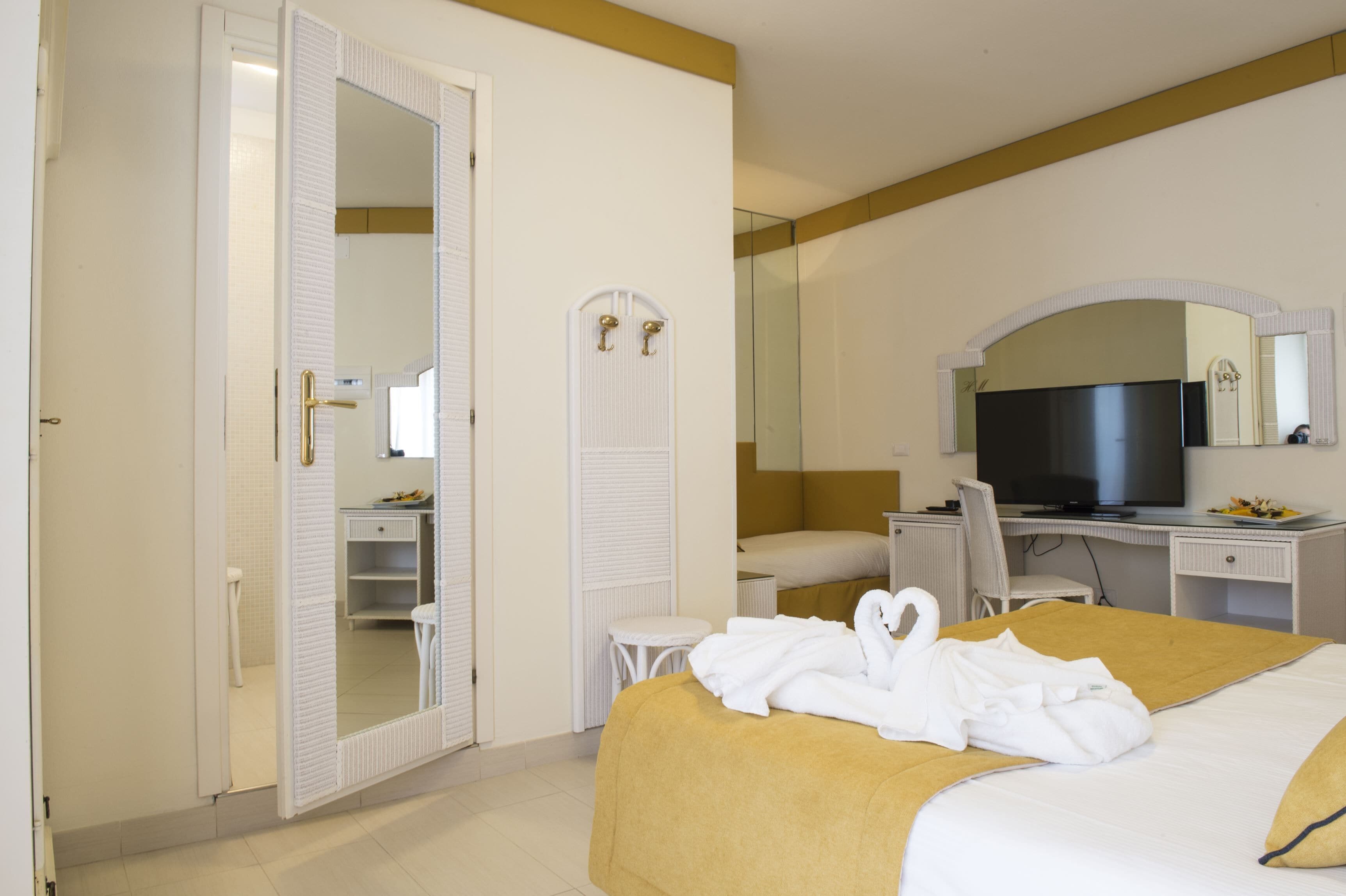 A hotel room with a bed, a desk, a television, and a wardrobe.