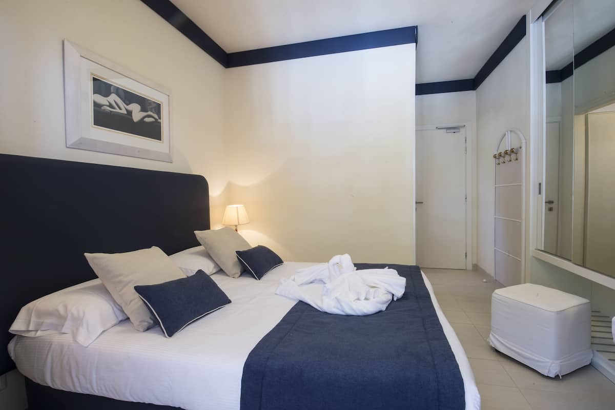 Une chambre d’hôtel avec un grand lit, un tableau encadré au mur, une lampe de chevet et un dressing.