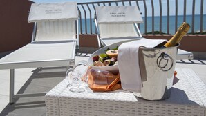 A poolside setting with lounge chairs, a bucket of champagne, and a bowl of fruit. - Park Hotel Maracaibo (Jesolo)