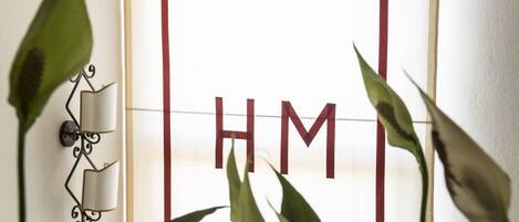 A room with a large window featuring a grid pattern and the letters "HM" prominently displayed.