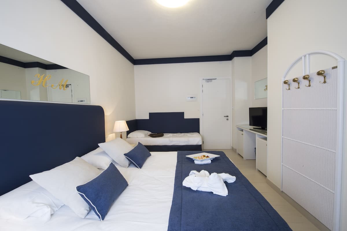 Une chambre d’hôtel avec un grand lit, un bureau, une télévision et une armoire.