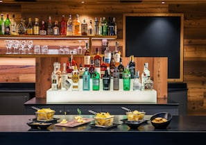 Een bar met meerdere flessen drank en glazen, en schalen met hapjes.