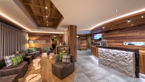 Ein modernes Interieur mit Holzakzenten, einer Rezeption und einer gemütlichen Sitzecke mit Sofas und Kamin.