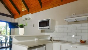 Une cuisine compacte avec des meubles blancs, un four à micro-ondes encastré et un petit réfrigérateur.