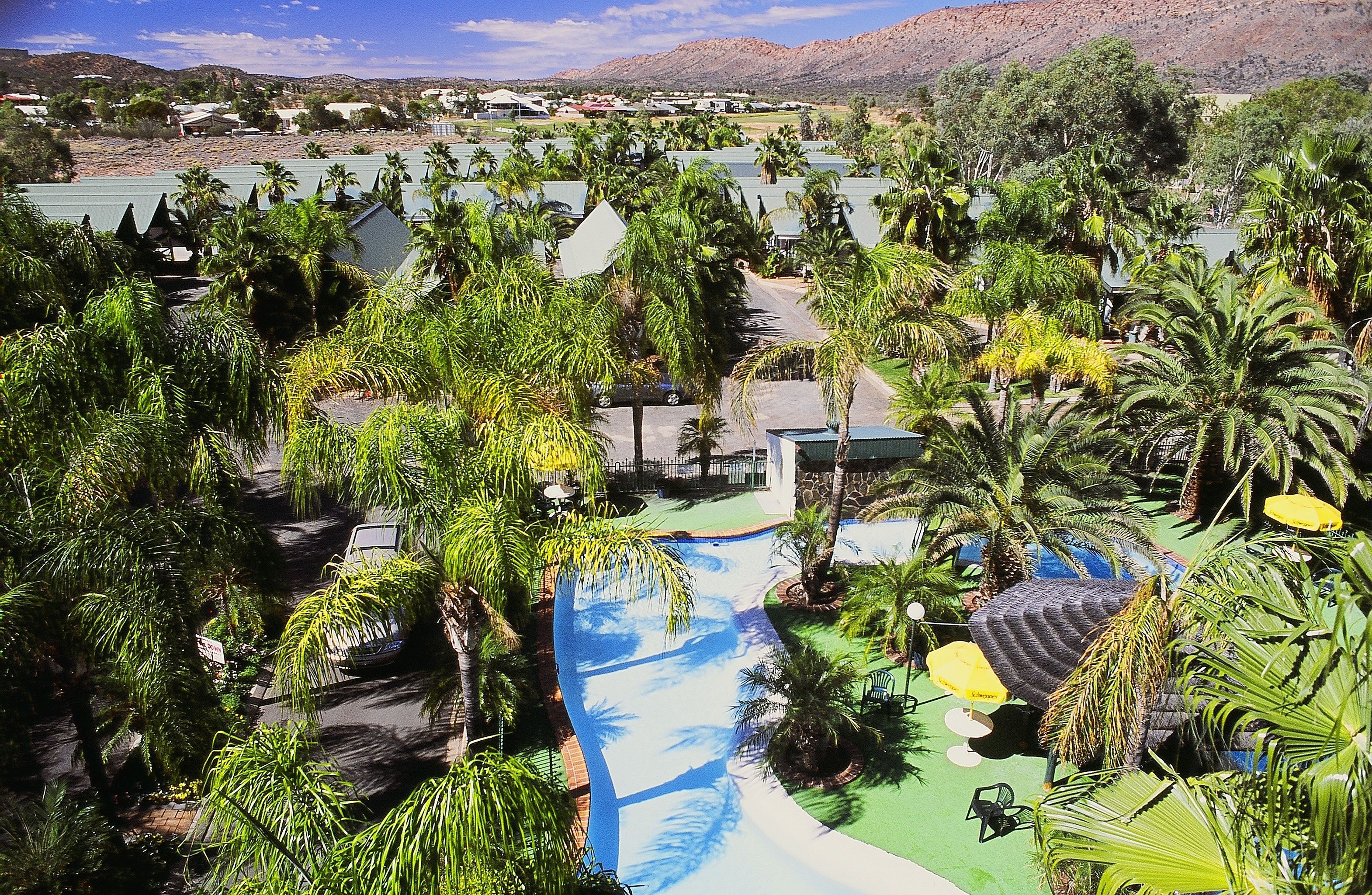 Un complexe hôtelier doté d’un toboggan aquatique, de palmiers et offrant une vue sur les montagnes lointaines.