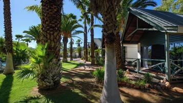 A resort with palm trees, a covered outdoor area, and a pathway.
