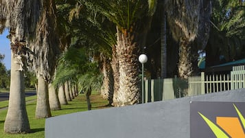 A sign for 'Desert Palms' with a clear view of palm trees and a well-maintained lawn.