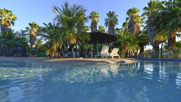 Una piscina al aire libre, sillones reclinables de piscina