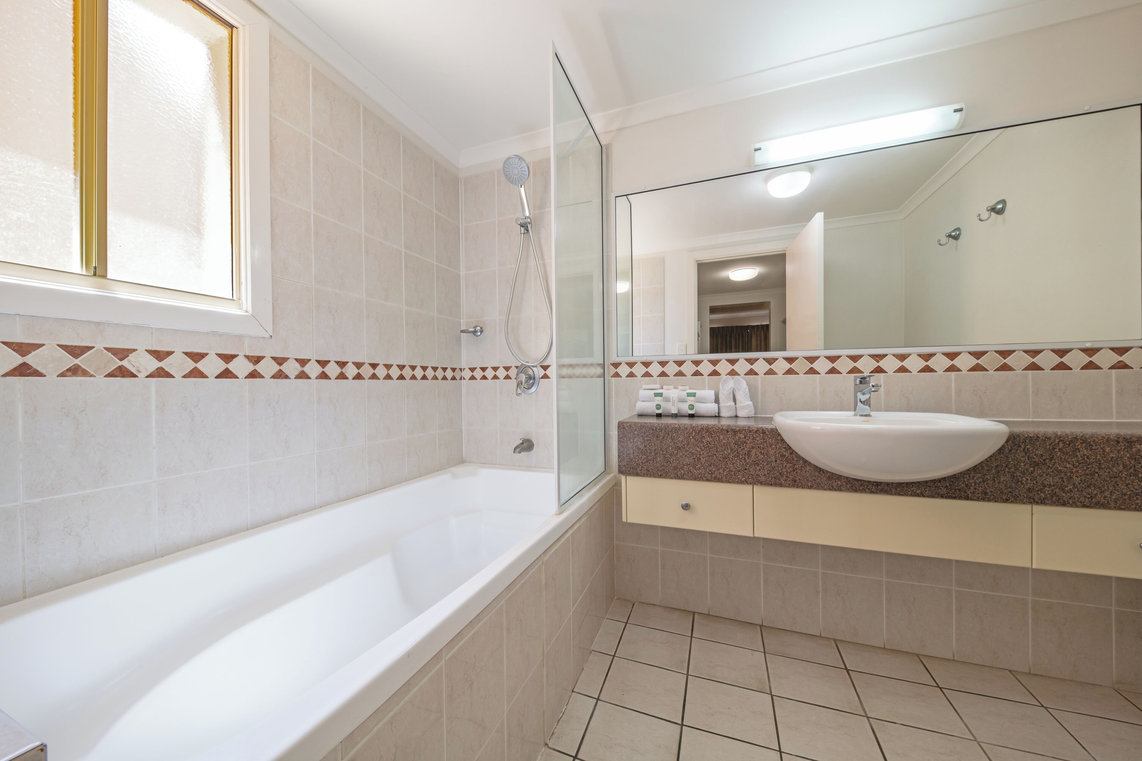 Un baño moderno con bañera, un espejo grande y un lavabo.