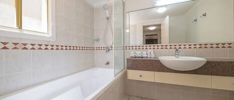 Un baño moderno con bañera, un espejo grande y un lavabo.
