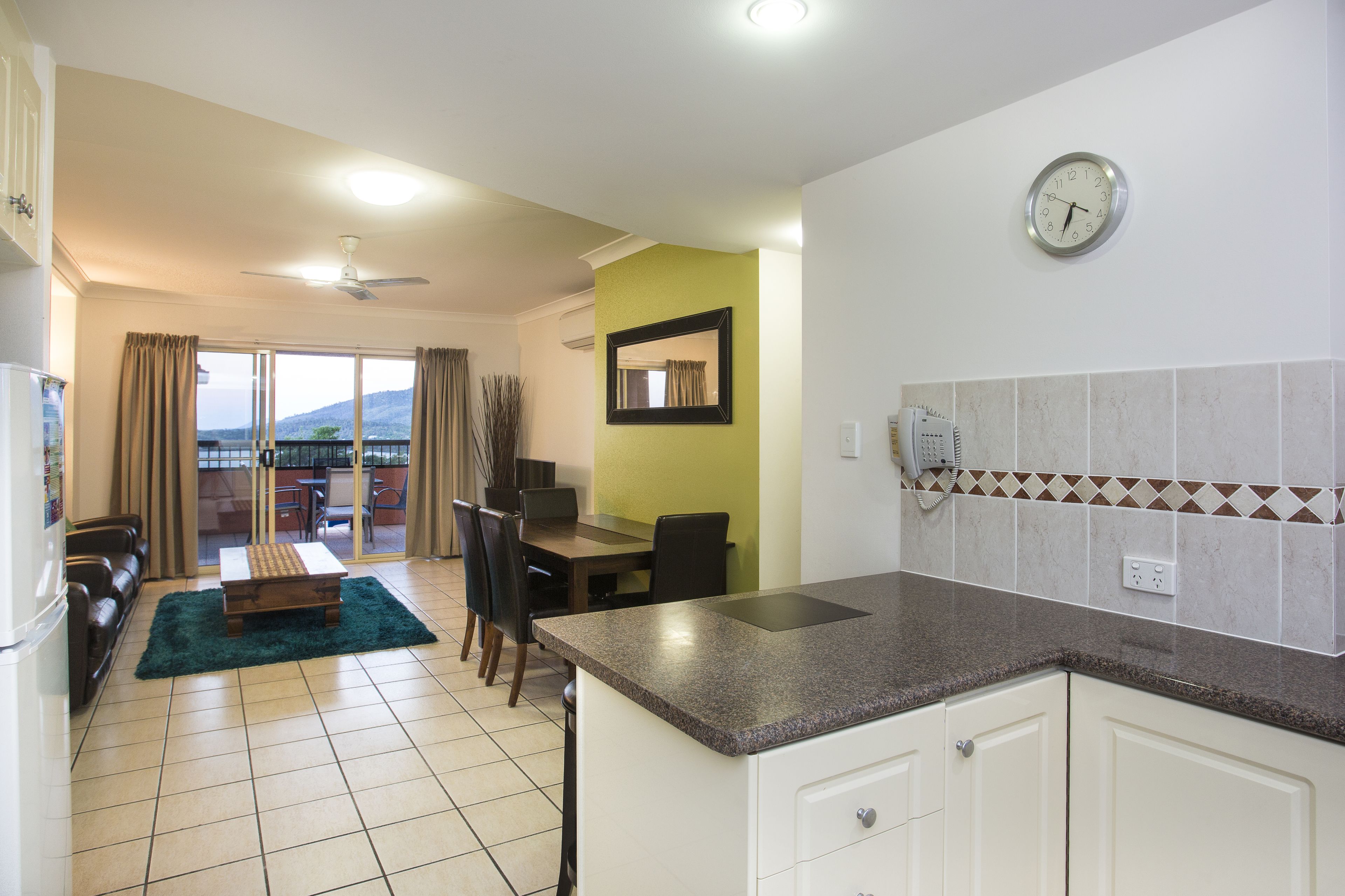 A modern kitchen with a granite countertop, white cabinets, and a dining area with a table and chairs.