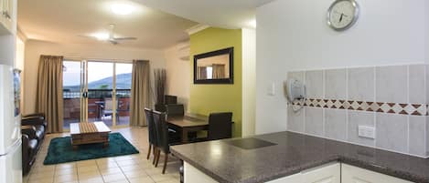 A modern kitchen with a granite countertop, white cabinets, and a dining area with a table and chairs.