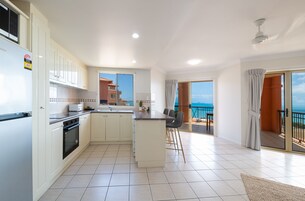 A modern kitchen with a central island, a dining area with a view, and a balcony with a view.