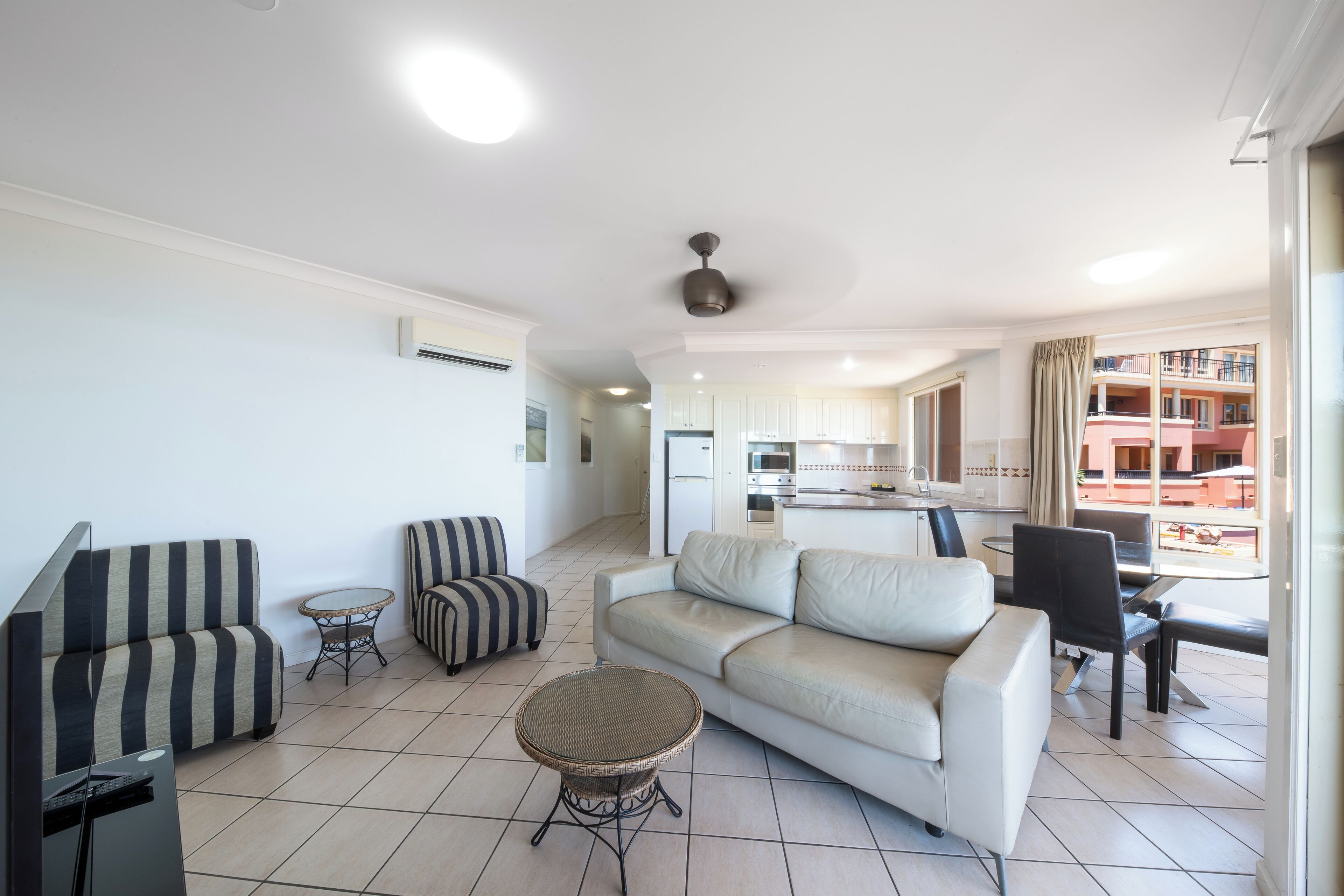 A modern living room with a sofa, armchairs, a small round table, and a TV.