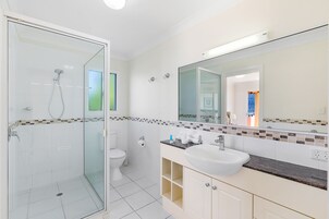 Un baño moderno con cabina de ducha de vidrio, inodoro y tocador con lavabo.