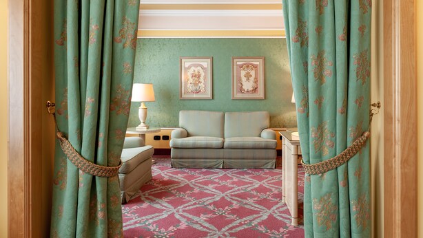 Una habitación con un sofá, dos cuadros en la pared y una alfombra estampada.