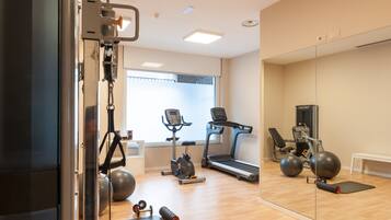 A gym with exercise equipment, a treadmill, and a mirror wall.