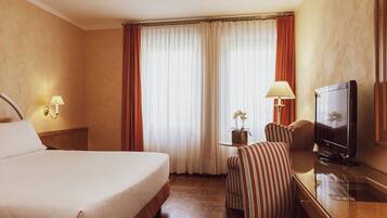 Une chambre d’hôtel avec un grand lit, une télévision, un bureau avec une lampe et une chaise.