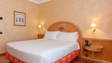 A neatly made bed with a wooden headboard, two bedside lamps, and a small bedside table with a telephone.