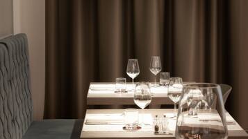A dining area with a table set for two, featuring a wine glass, a water glass, and cutlery.