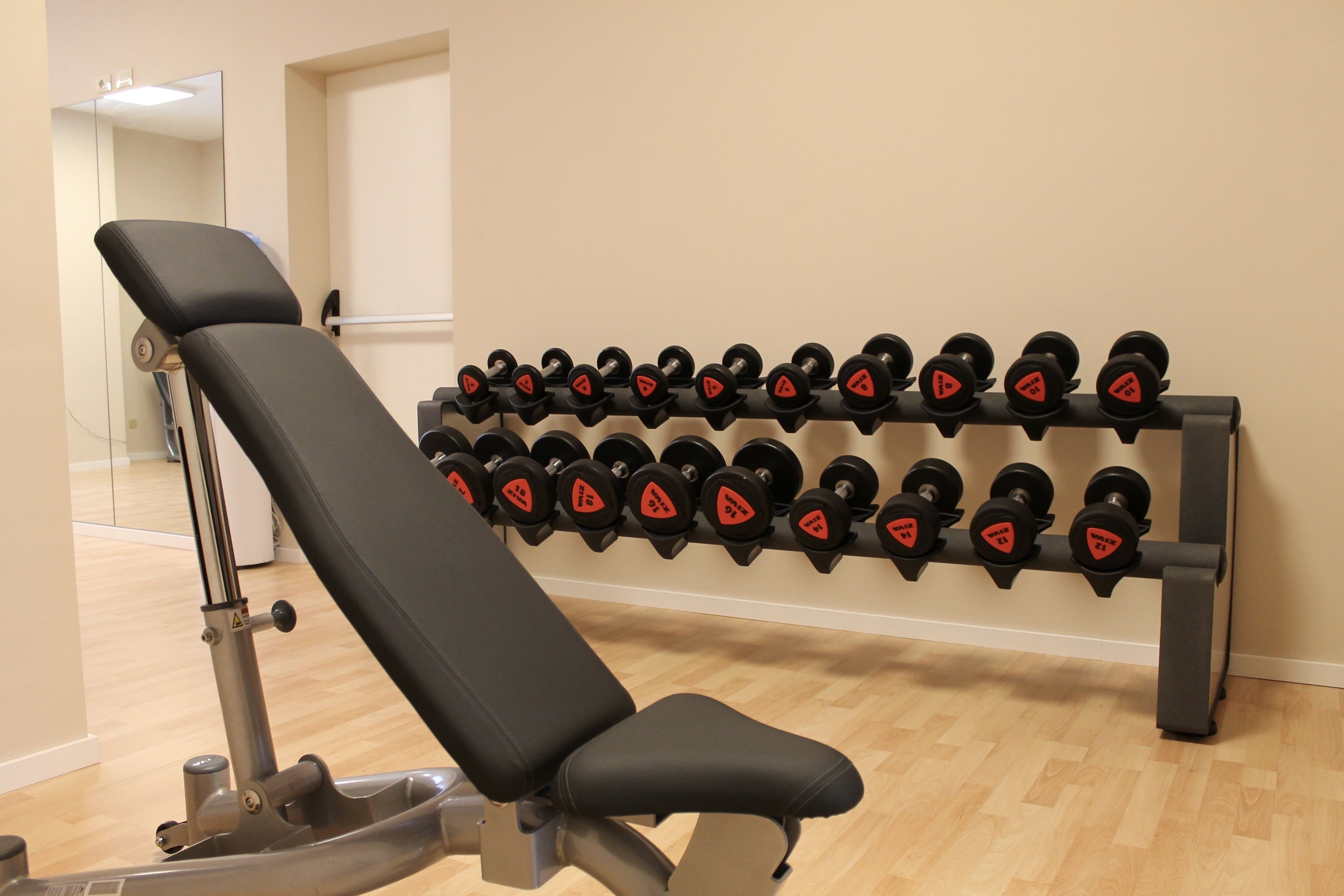 Ein Fitnessraum mit einer Bank und einem Hantelgestell.