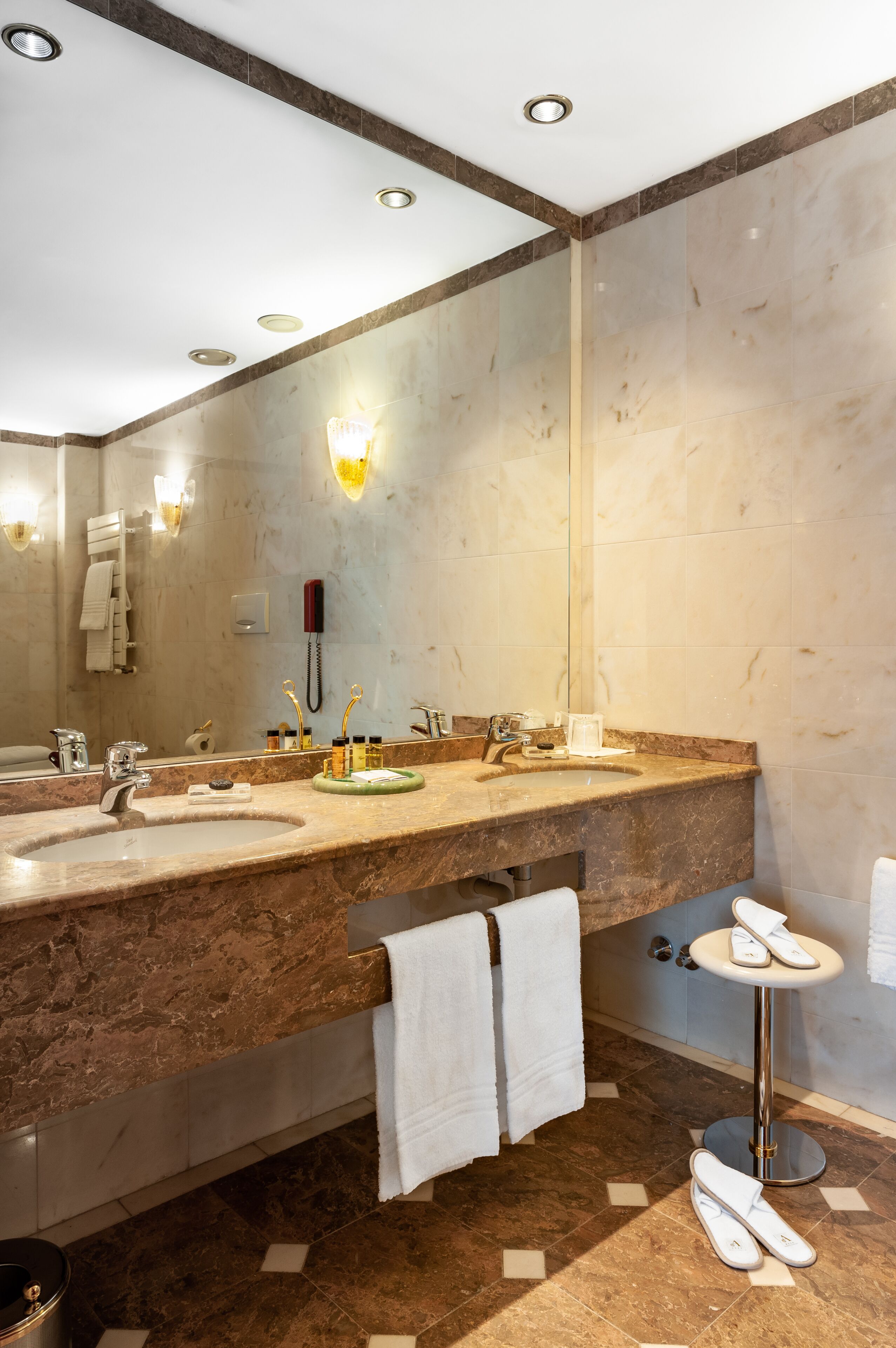 A modern bathroom with two sinks, a large mirror, a towel rack, and a phone.