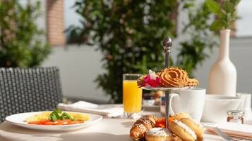 Ein Frühstückstisch mit Croissants, Gebäck und einem Glas Orangensaft.