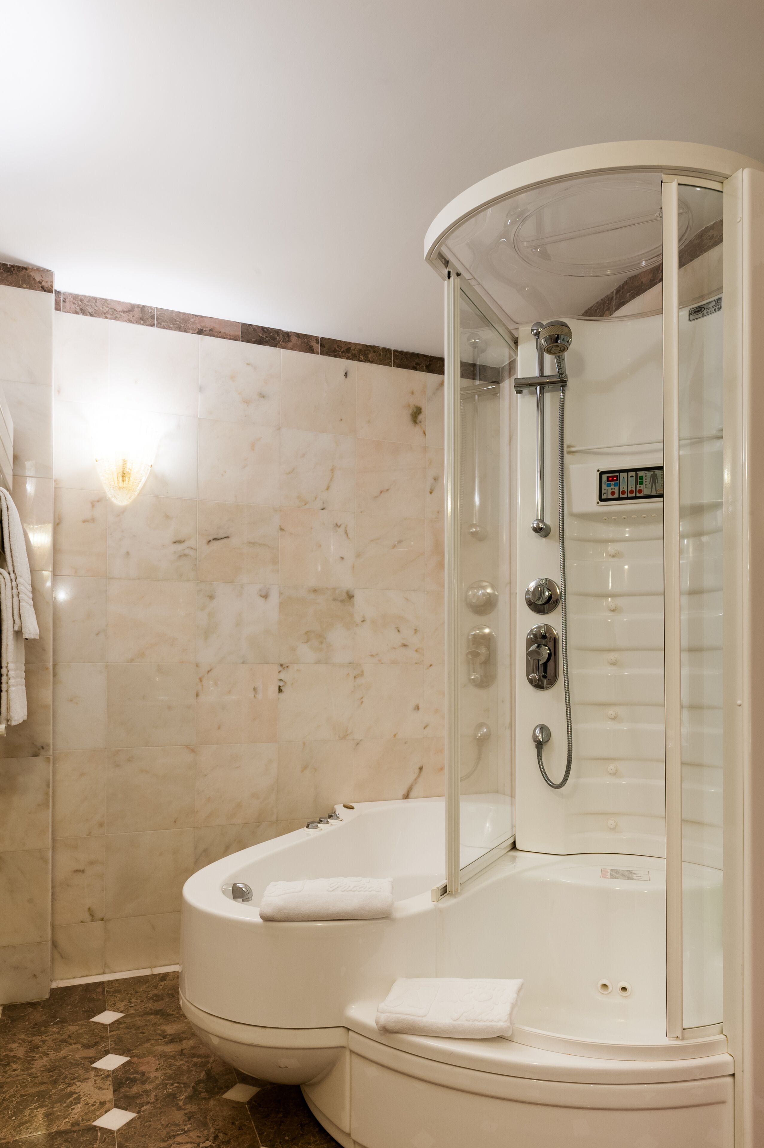 Un baño moderno con una bañera curva, ducha con cerramiento de vidrio y pared de azulejos de mármol.