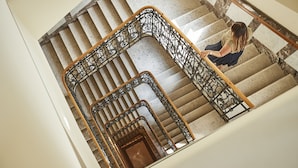Una imponente escalera con barandales de metal ornamentados y un pasamanos de madera, que conduce a un piso superior.