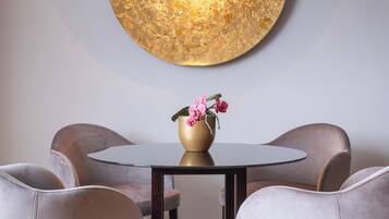 Uma sala de jantar com uma mesa redonda, quatro cadeiras e um candeeiro fixo na parede.