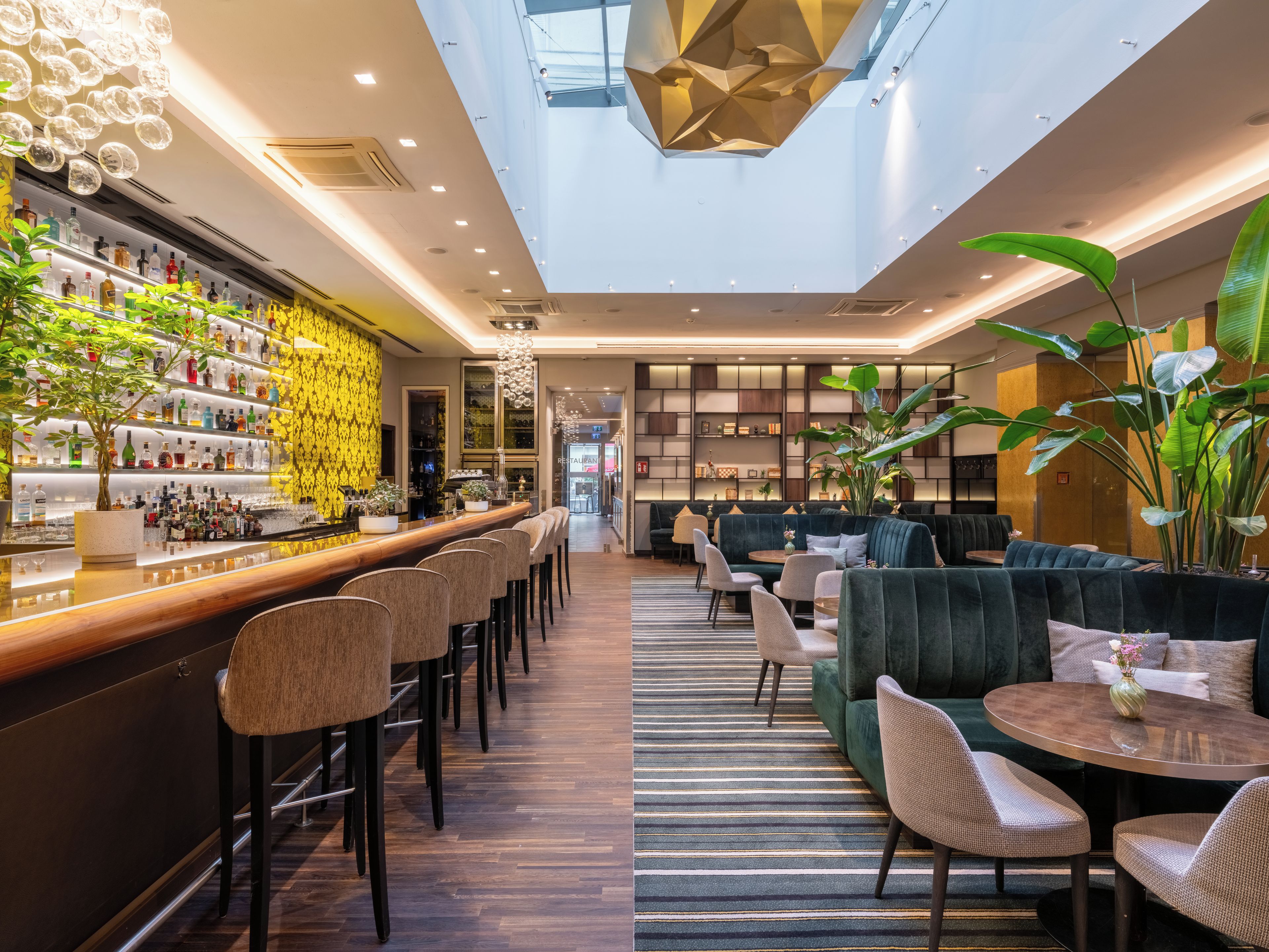 A bar area with a long counter, multiple chairs, and a seating area with couches and a table.