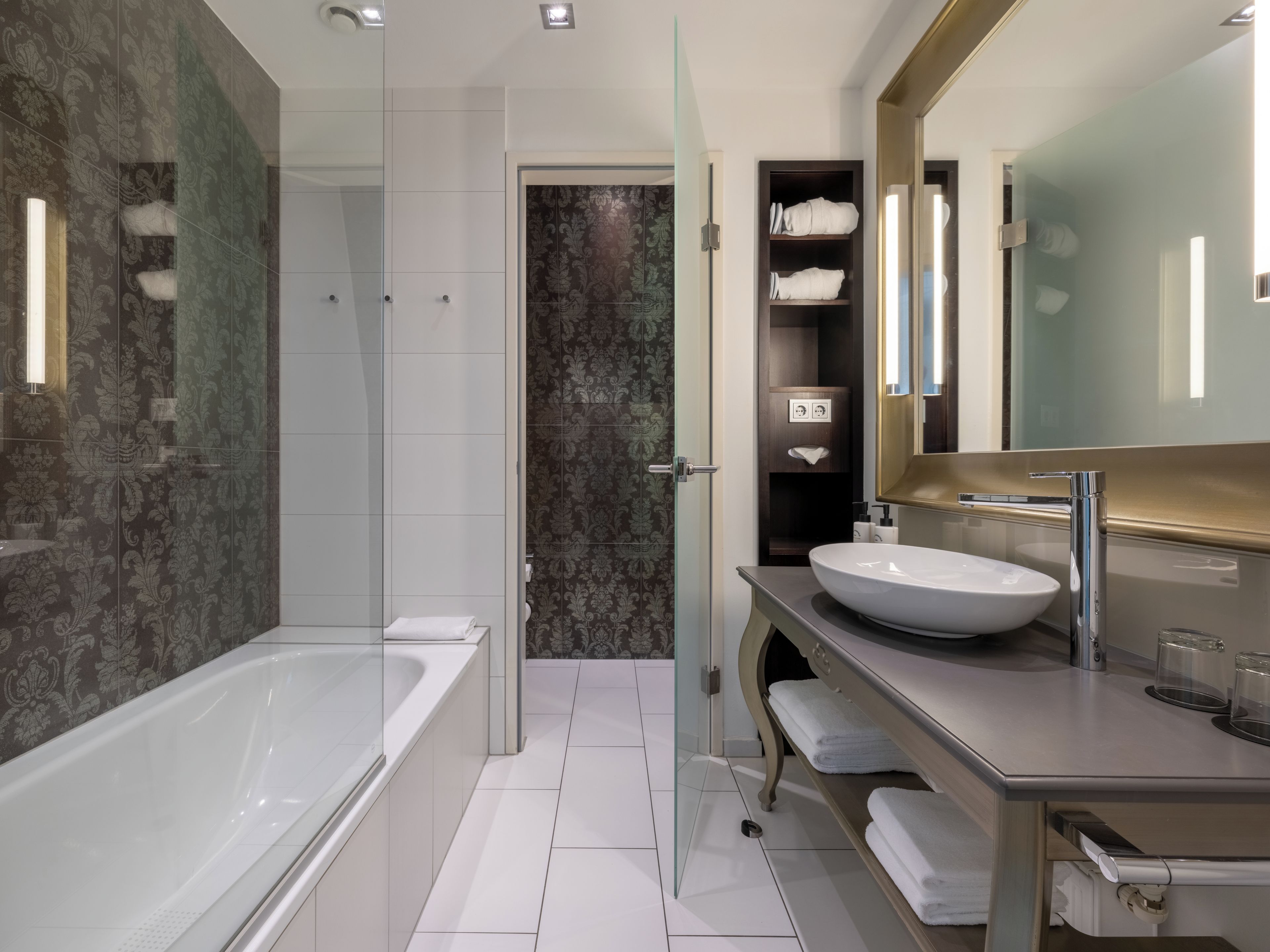 A modern bathroom with a glass-enclosed shower, a large bathtub, a vanity with a sink, and a mirror.