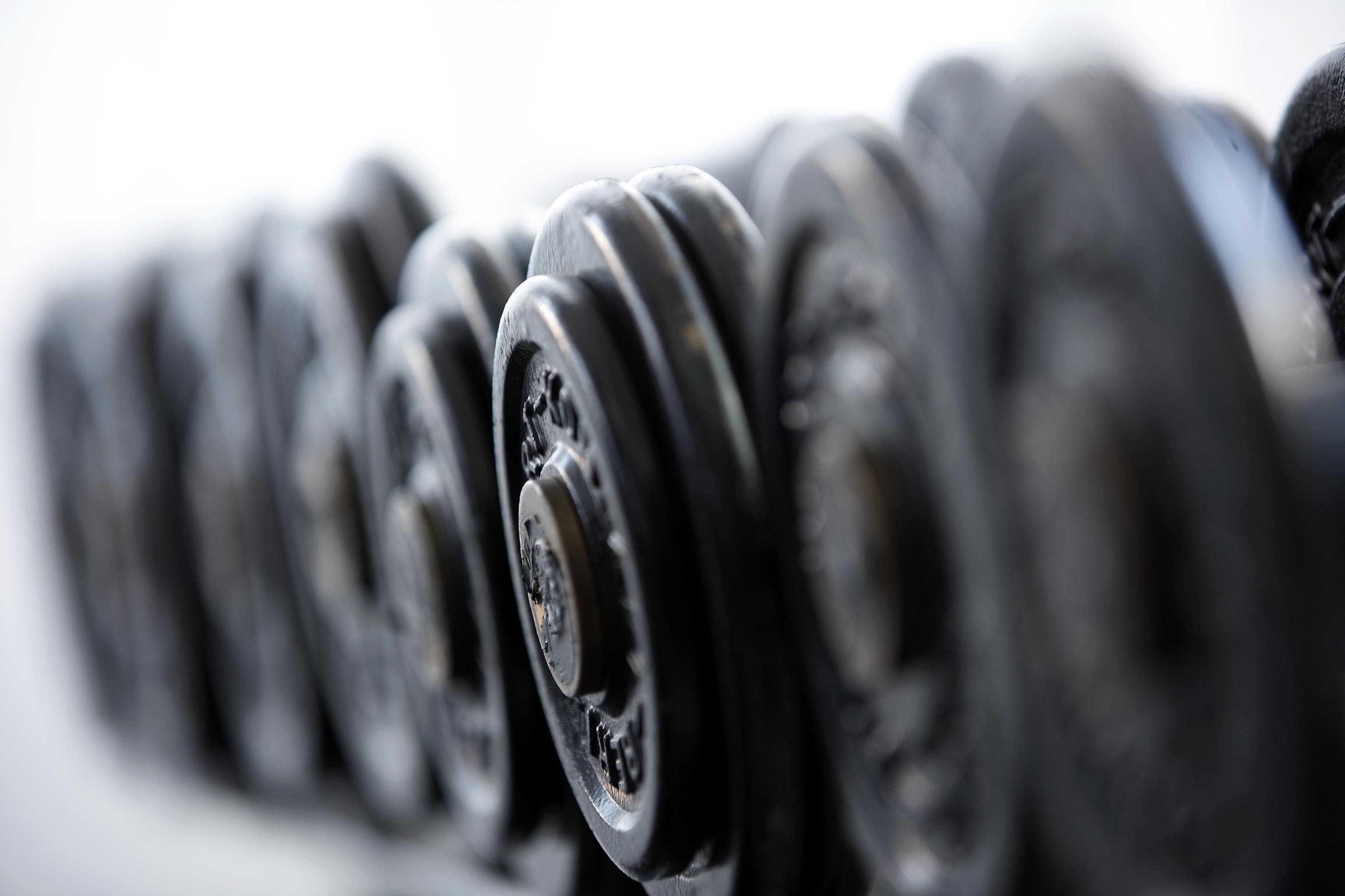 A close-up of a row of black dumbbells with visible weight markings.