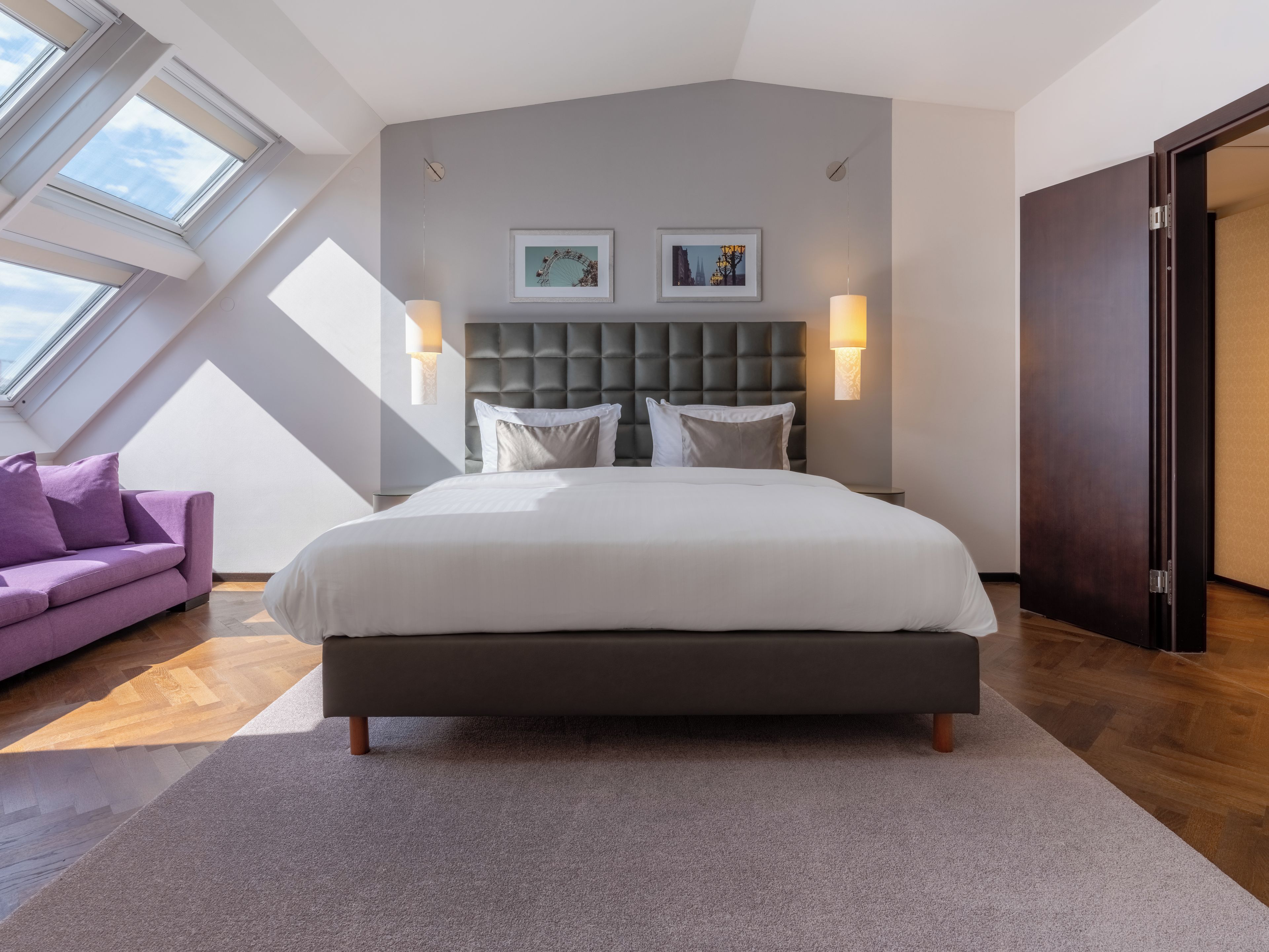 Ein modernes Schlafzimmer mit einem großen Bett, einer Couch und einem Oberlicht.