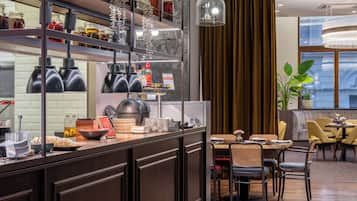 Cocina moderna con comedor, que incluye una encimera con frascos, una lámpara colgante y vistas de la ciudad a través de amplias ventanas.