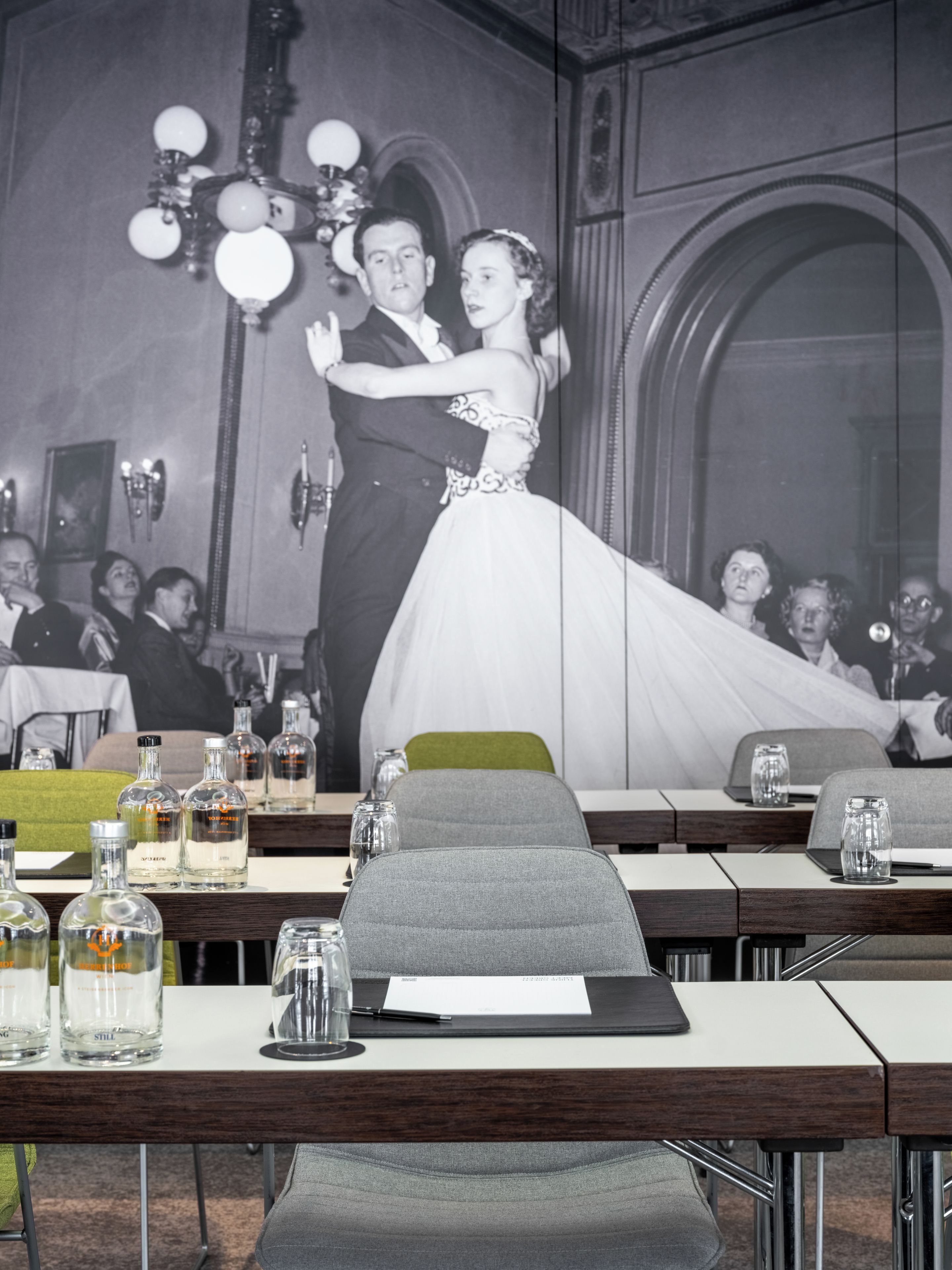 A wedding reception with a large wedding photo backdrop, tables with glasses and bottles, and a modern interior design.