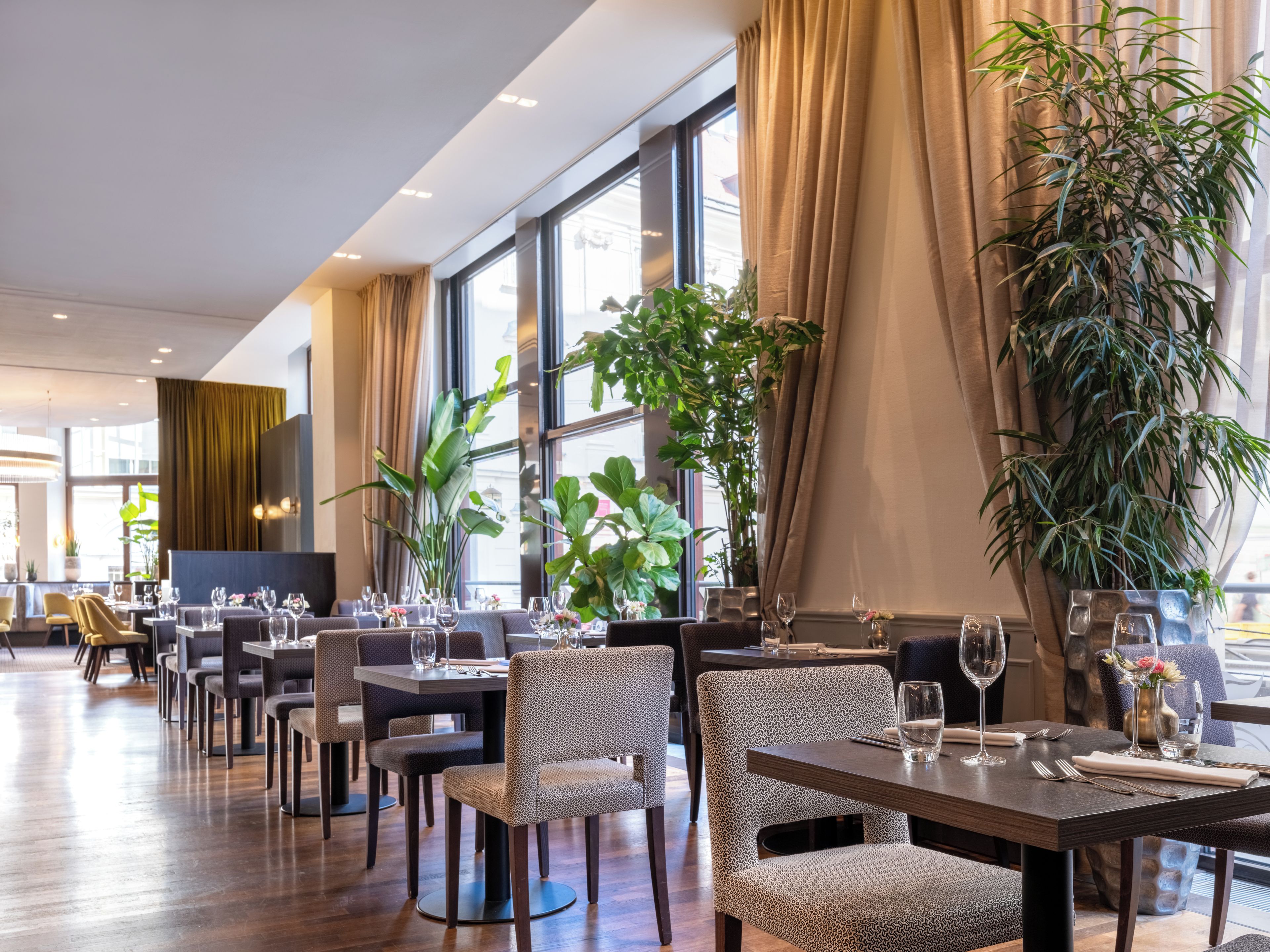Un interior de restaurante con mesas, sillas y grandes ventanales.