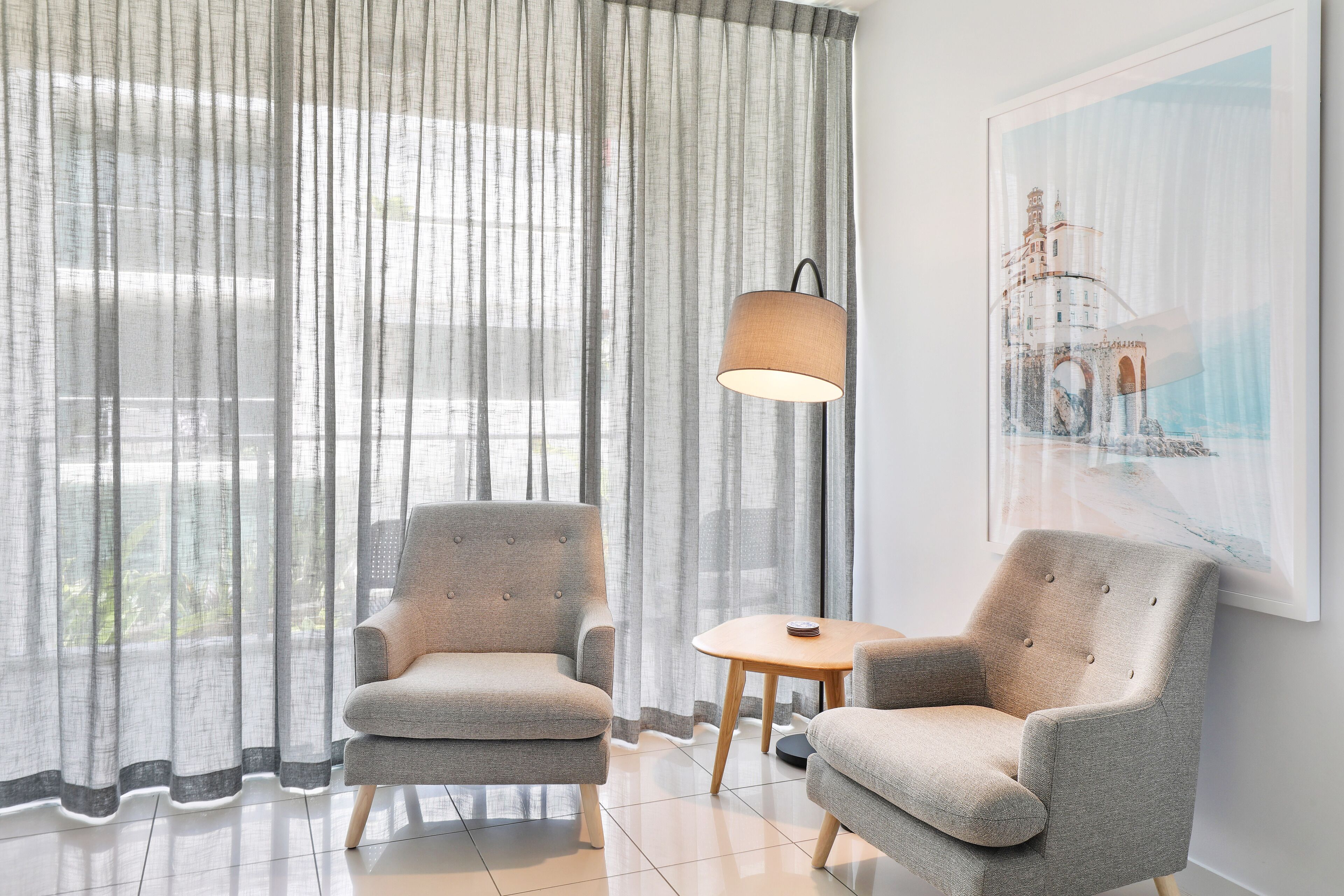 Una habitación moderna con dos sillones grises, una mesita redonda y una lámpara.
