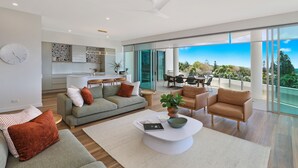 Un salon moderne comprenant un canapé, une table basse et des fauteuils, un coin cuisine et un balcon avec vue.