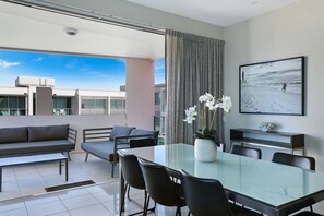 A modern dining area with a glass table, black chairs, and a white orchid vase. - Element on Coolum Beach (Coolum Beach)