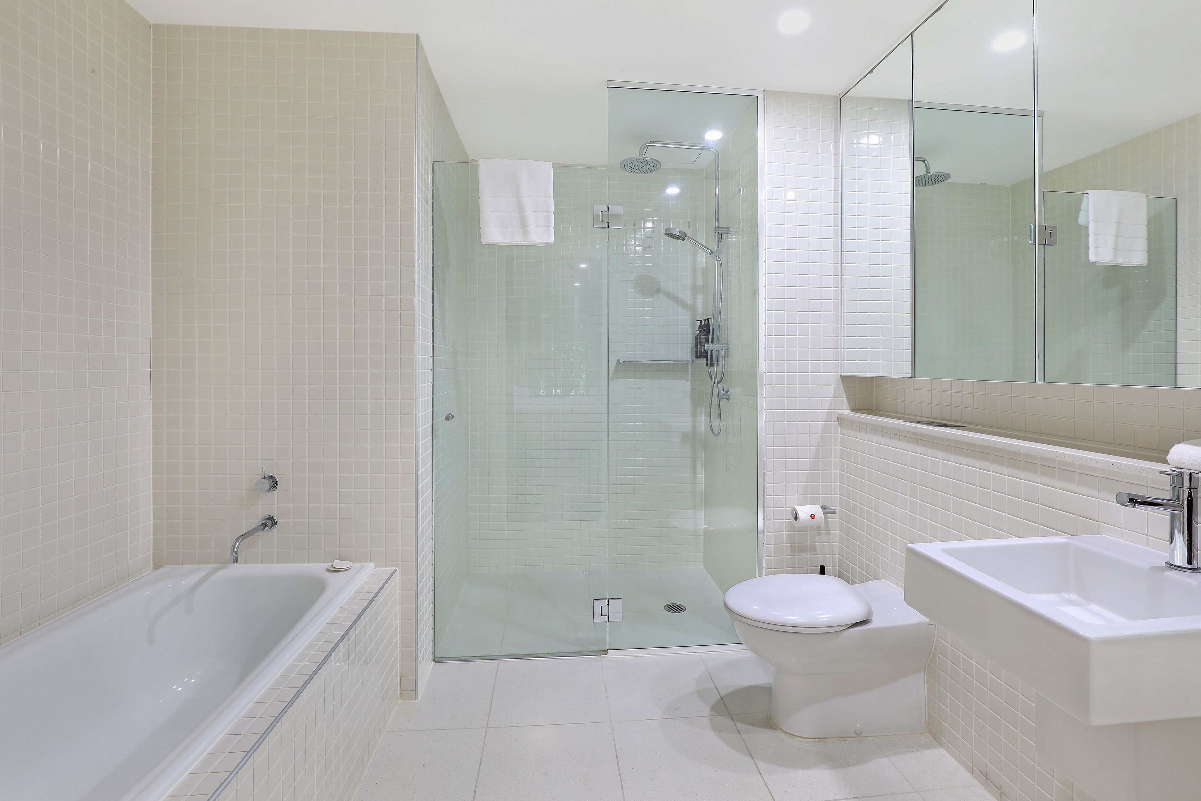 A modern bathroom with a glass-enclosed shower, a freestanding bathtub, a toilet, and a sink.
